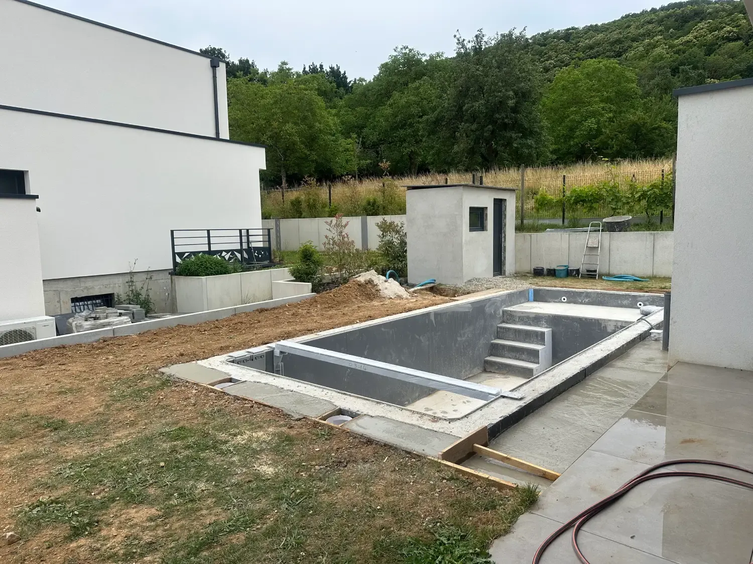 Bassin encore vide avec escalier et cabanon maçonné au fond du jardin