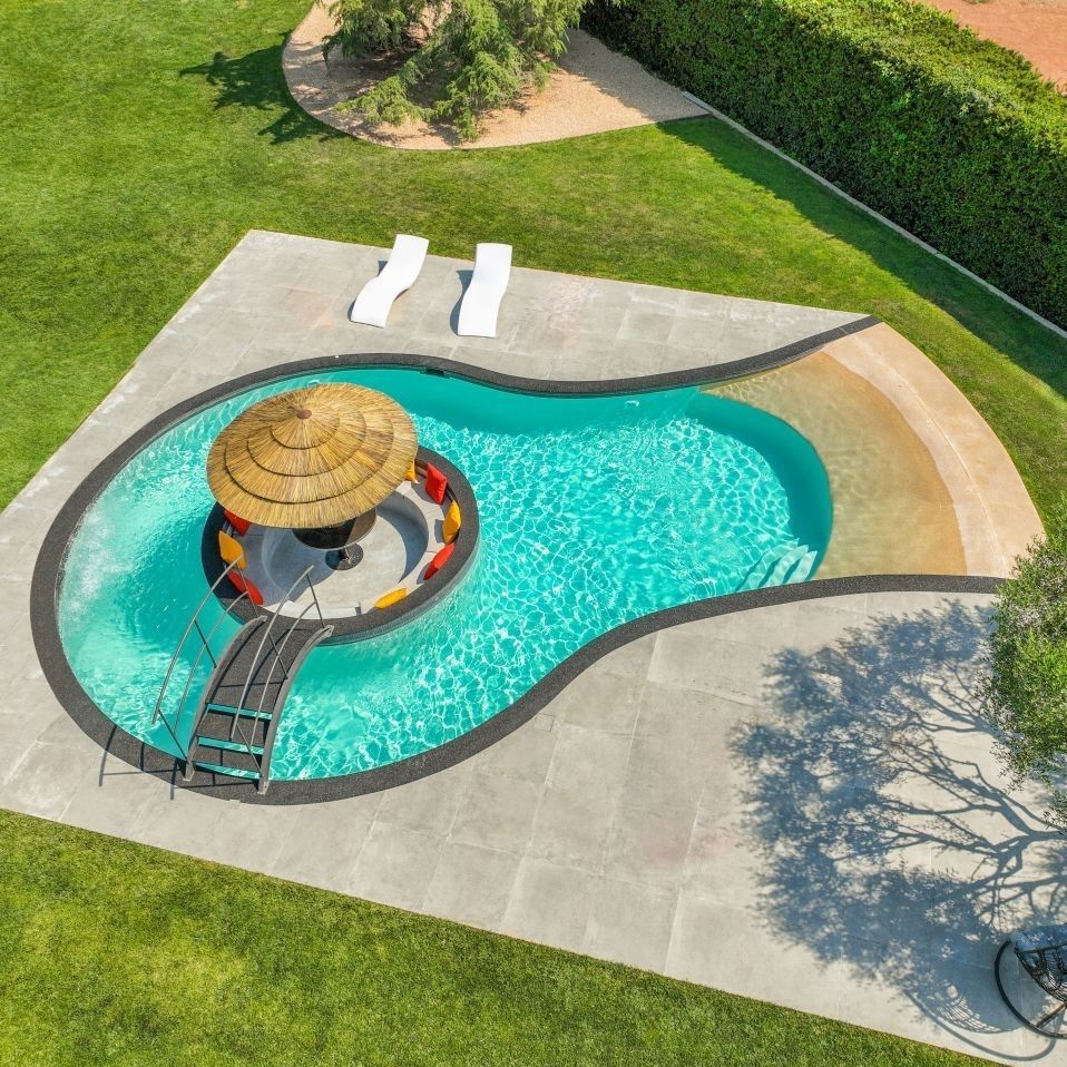 Piscine en béton de forme ronde avec ilot au centre et un pont pour y accéder