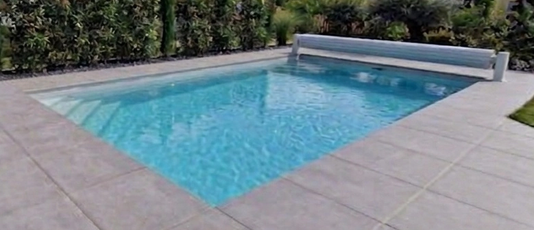Piscine coque enterrée, modèle KAREN. Avec volet hors sol et contour en dalles de pierre.
