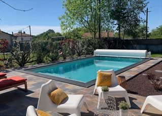 Piscine en béton avec margelle en pierre noire et volet hors sol