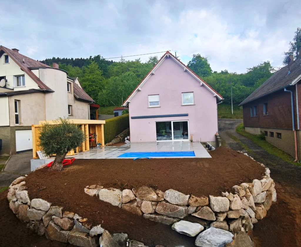 Installation d'une piscine coque à Grendelbruch avec aménagements extérieurs : création d'une terrasse, mise à niveau du sol, enrochement.